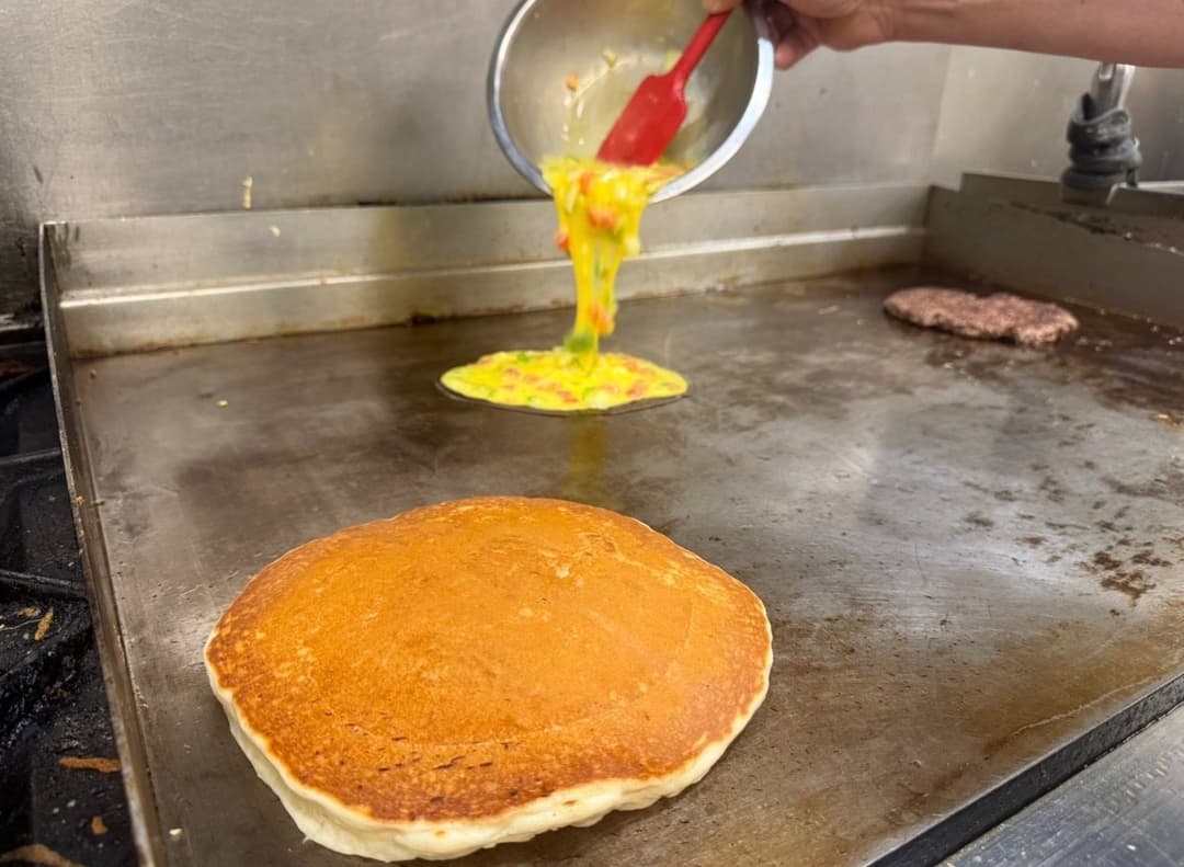 Pancakes and omelets cooking on the griddle